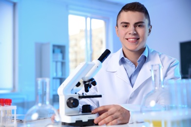Male scientist with modern microscope in chemistry laboratory, space for text