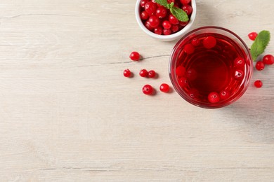 Photo of Tasty refreshing cranberry juice, mint and fresh berries on light wooden table, flat lay. Space for text