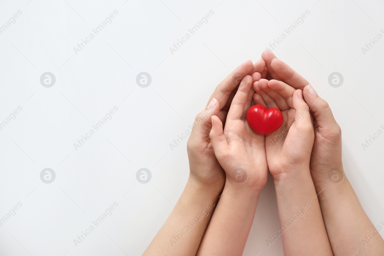 Photo of Young woman and child holding red heart on light background, top view