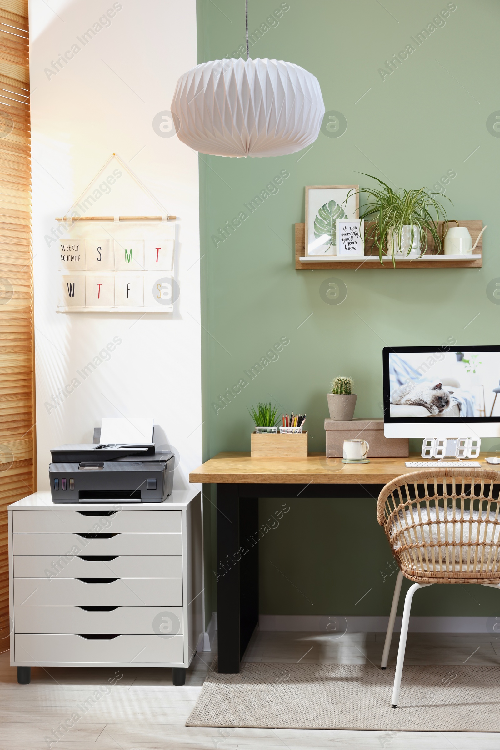 Photo of Stylish workplace with computer, printer and houseplant near olive wall at home