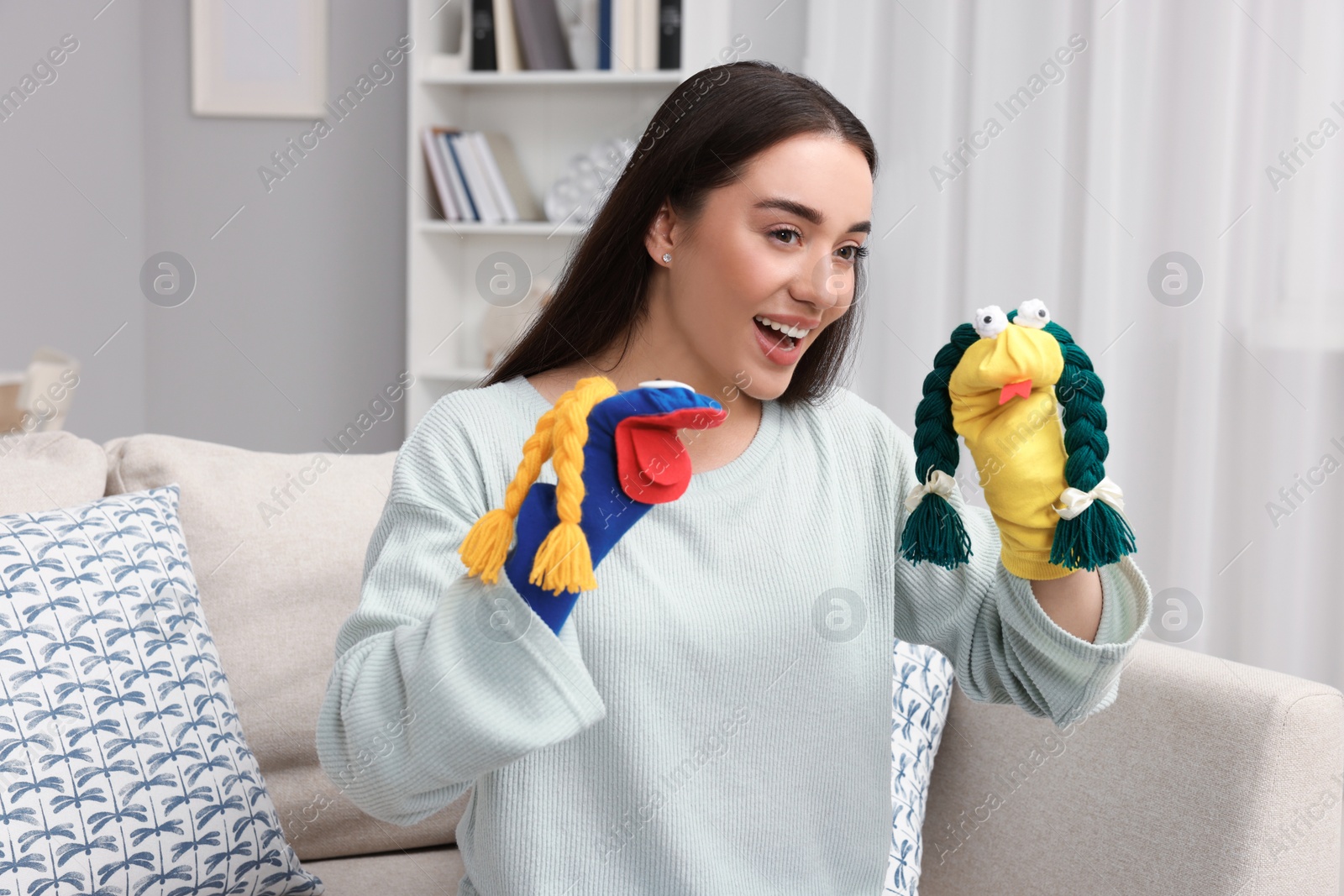 Photo of Happy woman performing puppet show on sofa at home