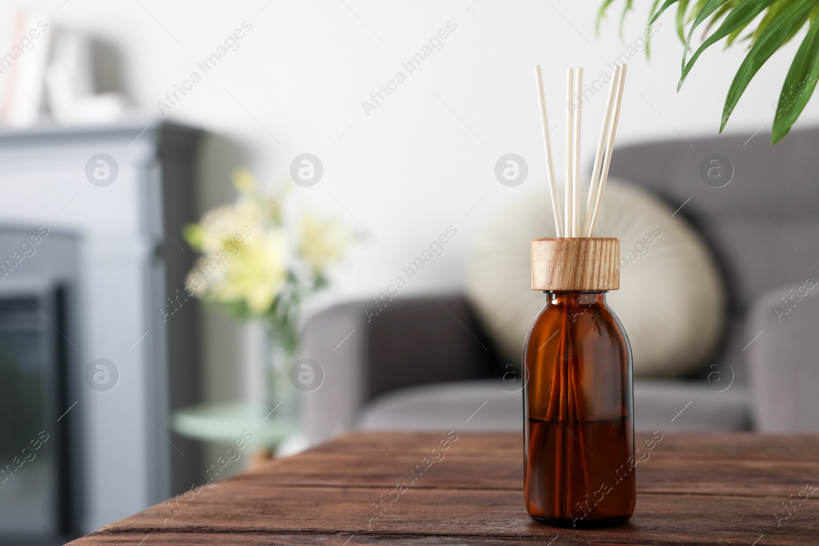 Photo of Aromatic reed air freshener on wooden table in room. Space for text