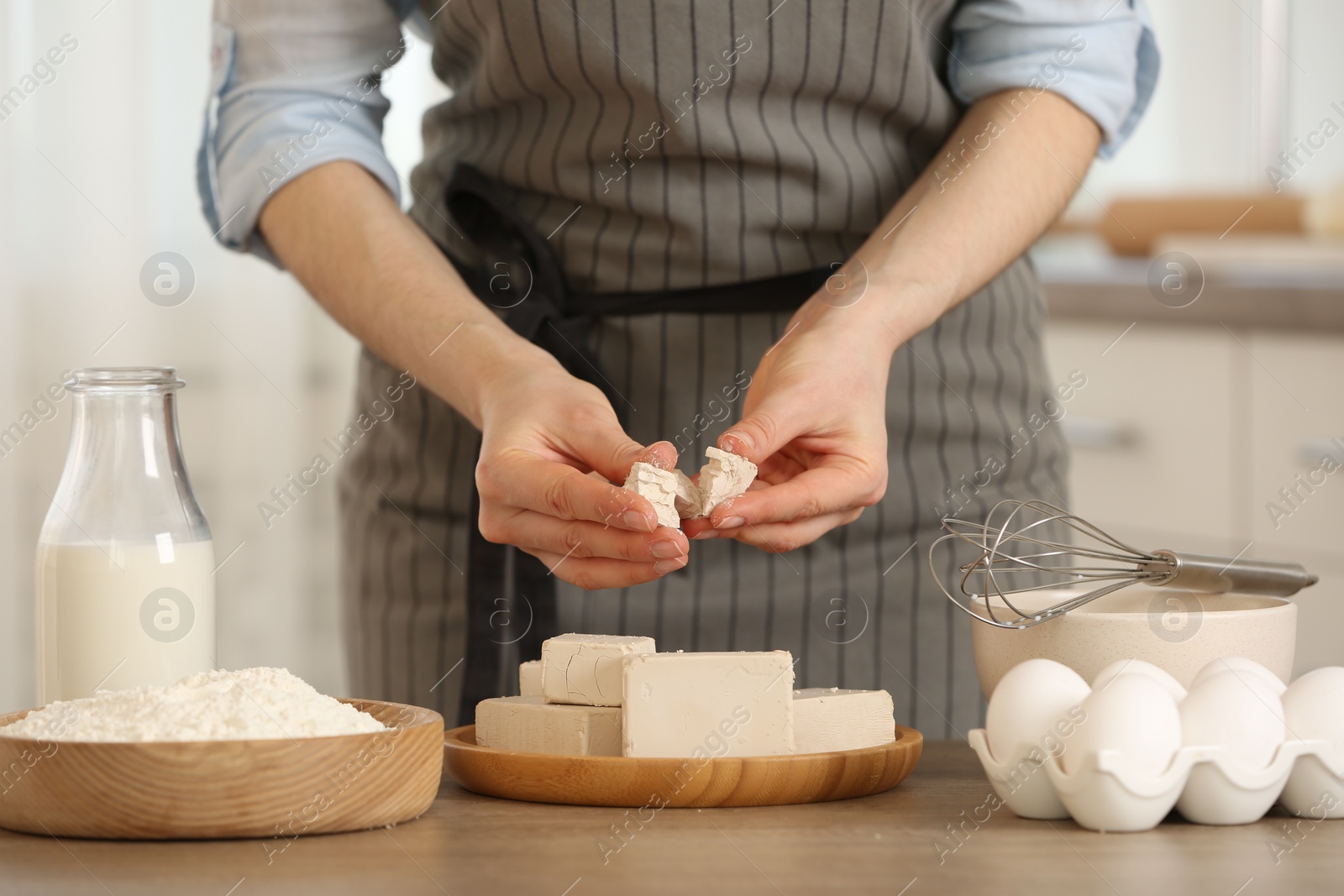 Photo of Woman with compressed yeast at wooden table indoors, closeup