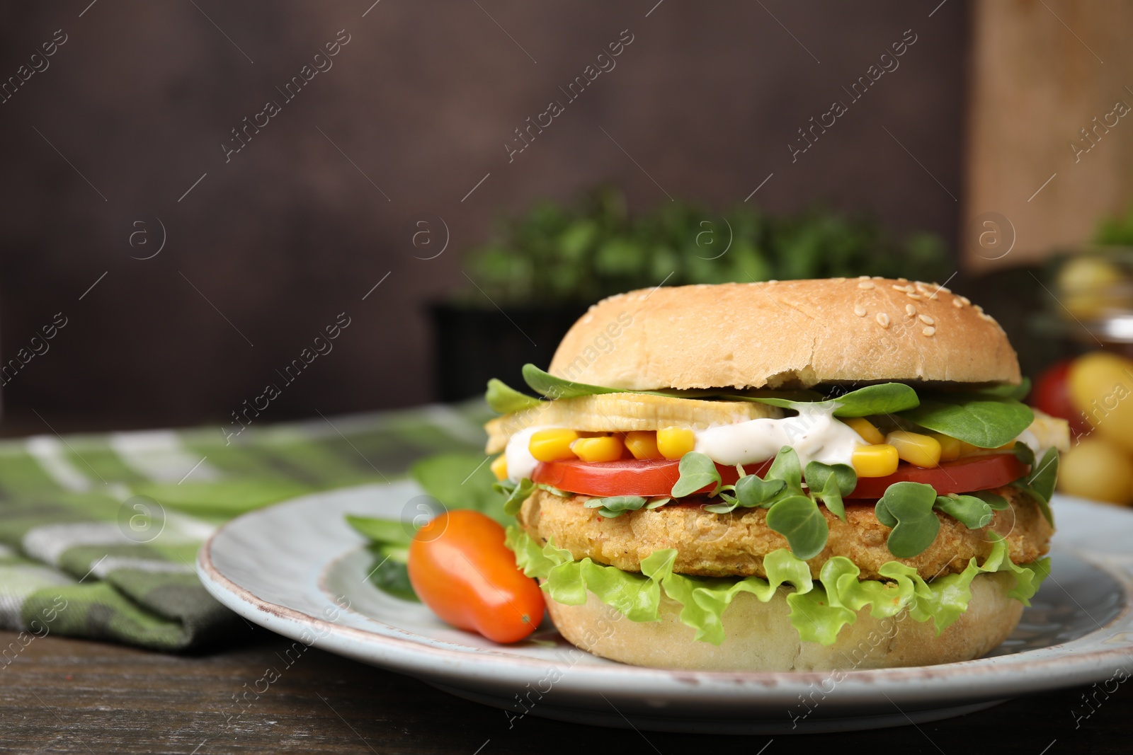 Photo of Tasty vegan burger with vegetables, patty and microgreens on wooden table, closeup. Space for text