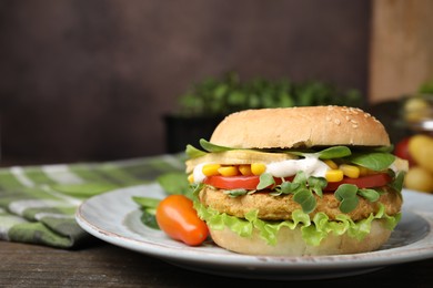 Photo of Tasty vegan burger with vegetables, patty and microgreens on wooden table, closeup. Space for text