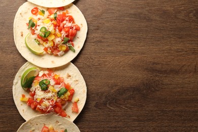 Photo of Delicious tacos with vegetables and lime on wooden table, top view. Space for text