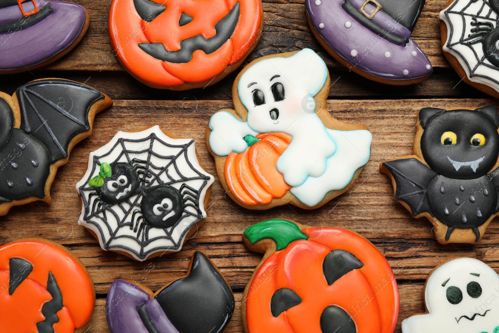 Photo of Tasty Halloween cookies on wooden table, flat lay