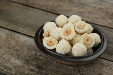 Photo of Delicious candies with coconut flakes and hazelnut on wooden table, closeup