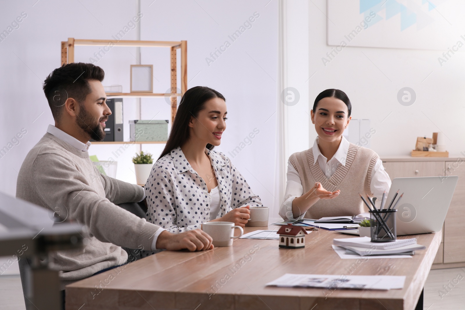 Photo of Real estate agent working with young couple in office. Mortgage concept