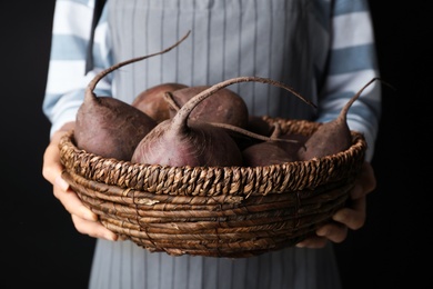 Photo of Woman holding bowl with beets on black background