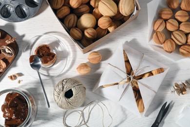 Flat lay composition of walnut shaped cookies filled with caramelized condensed milk on white wooden table. Homemade pastry packed for present