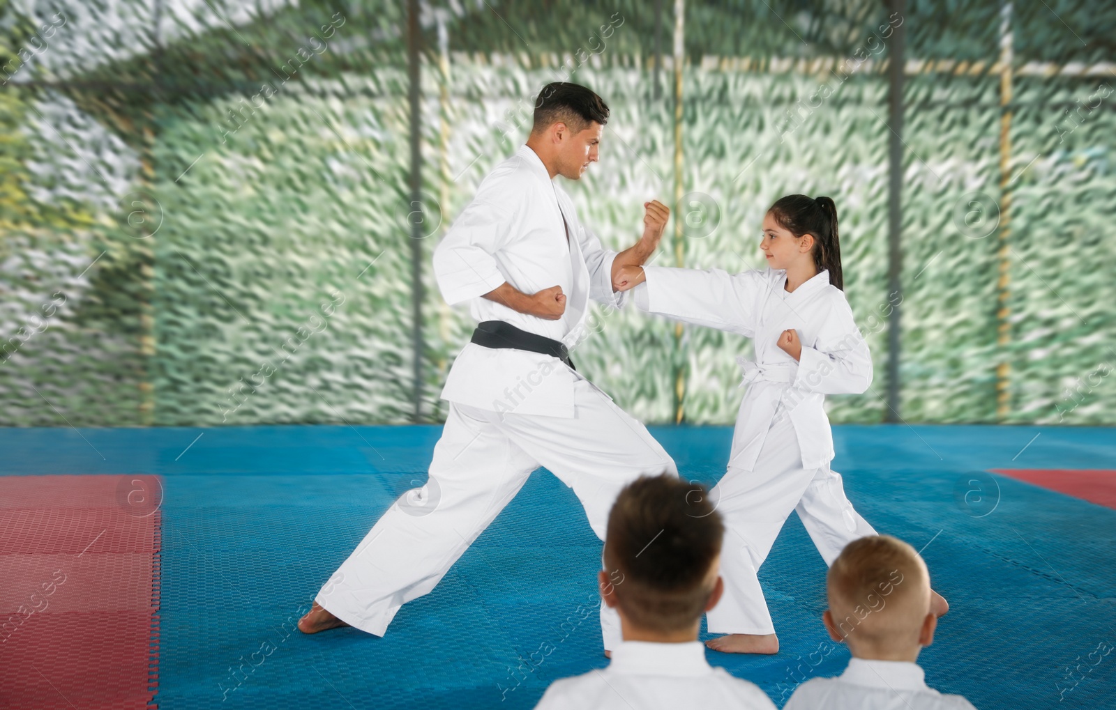 Photo of Girl practicing karate with coach on tatami outdoors