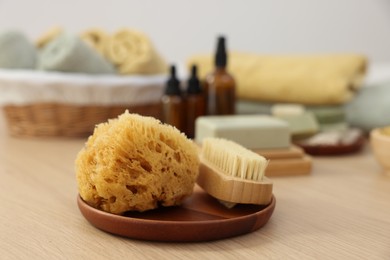 Photo of Sponge and brush on light wooden table. Spa therapy