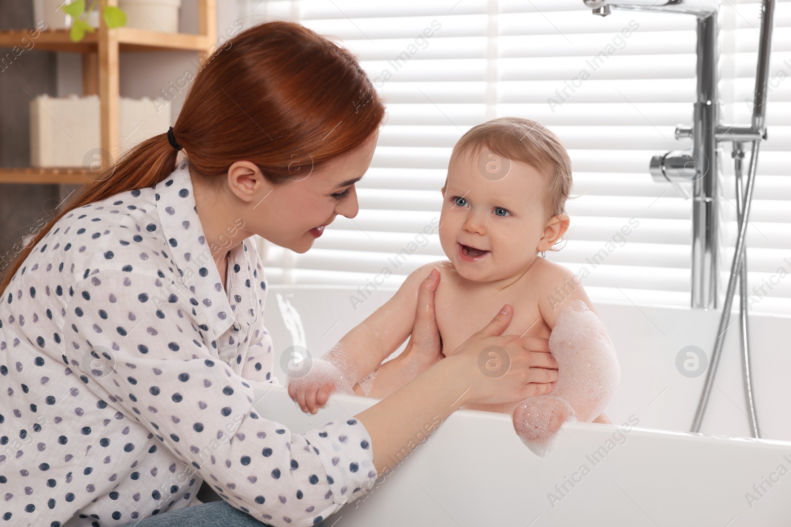 Photo of Mother washing her little baby in tub at home