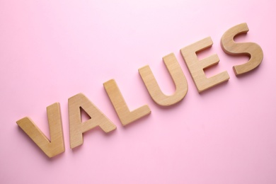 Photo of Word VALUES made of wooden letters on pink background, flat lay