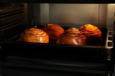 Photo of Baking delicious spiral buns in electric oven
