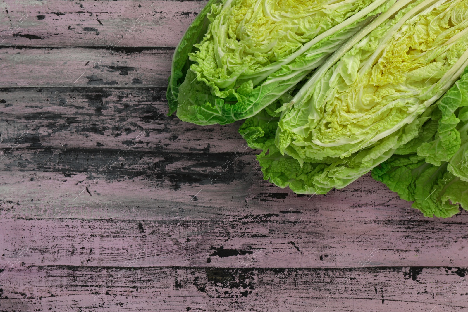 Photo of Cut fresh ripe Chinese cabbages on rustic table, flat lay. Space for text