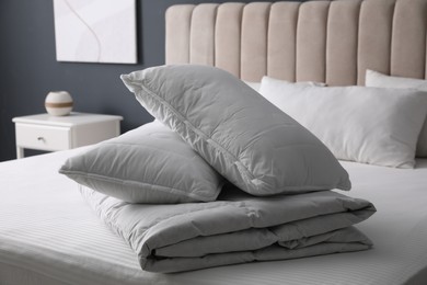 Photo of Soft folded blanket and pillows on bed indoors