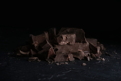 Pieces of tasty dark chocolate on black table