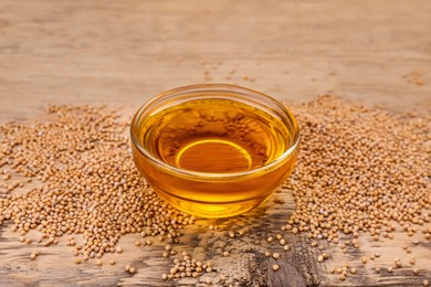 Photo of Bowl of natural oil and mustard seeds on wooden table