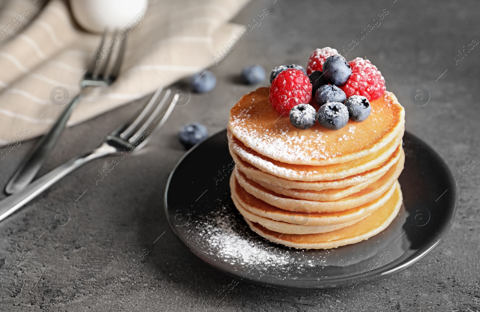 Photo of Tasty pancakes with berries and sugar powder on plate