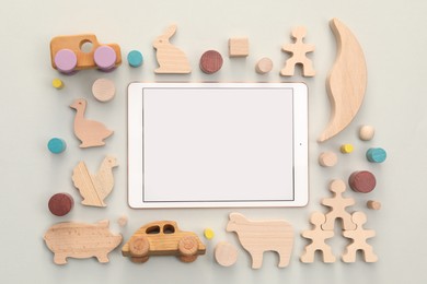 Modern tablet and wooden toys on light background, flat lay. Space for text