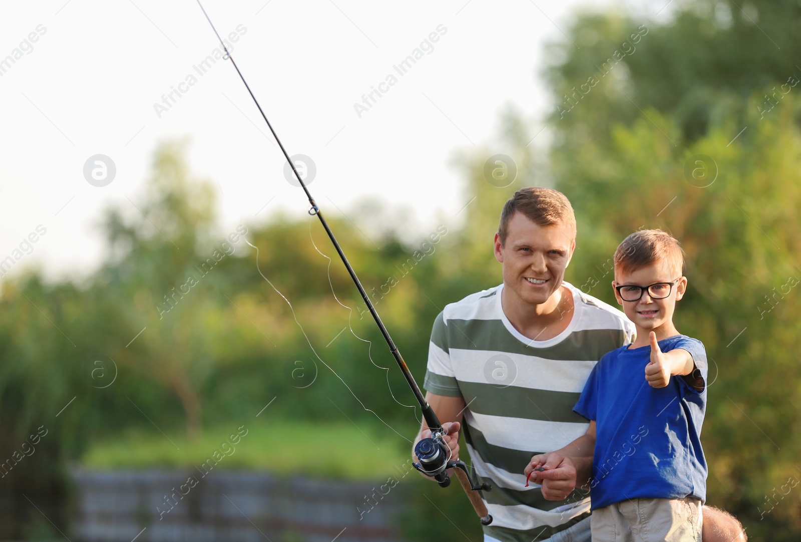 Photo of Dad and son fishing together on sunny day