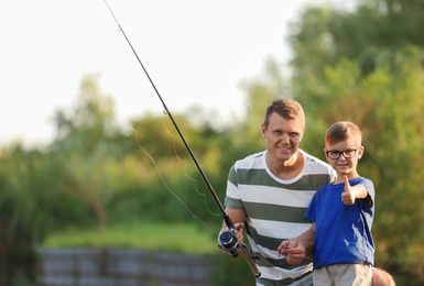 Dad and son fishing together on sunny day