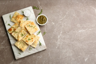 Photo of Delicious focaccia bread on marble table, flat lay. Space for text