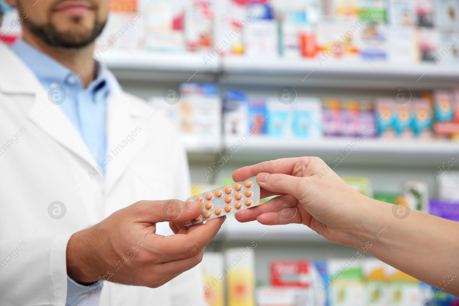 Image of Professional pharmacist giving pills to customer in drugstore, closeup