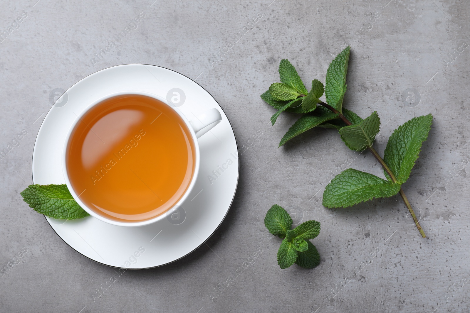 Photo of Cup of hot aromatic mint tea on light grey table, flat lay
