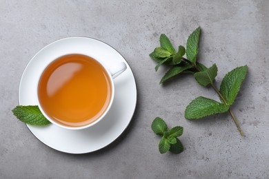 Cup of hot aromatic mint tea on light grey table, flat lay