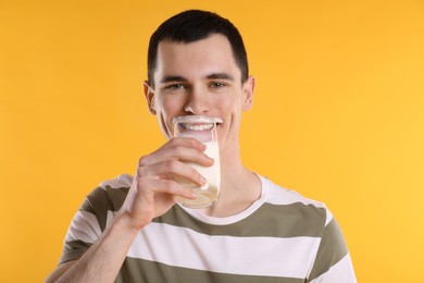 Milk mustache left after dairy product. Man drinking milk on orange background