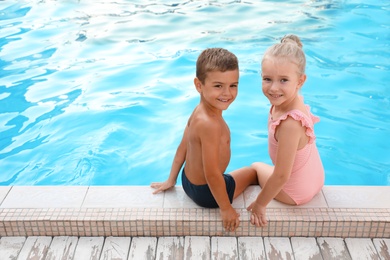 Cute little children sitting at outdoor swimming pool