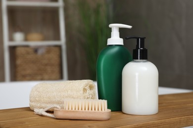 Photo of Bottles of shower gels, loofah and brush on wooden table indoors