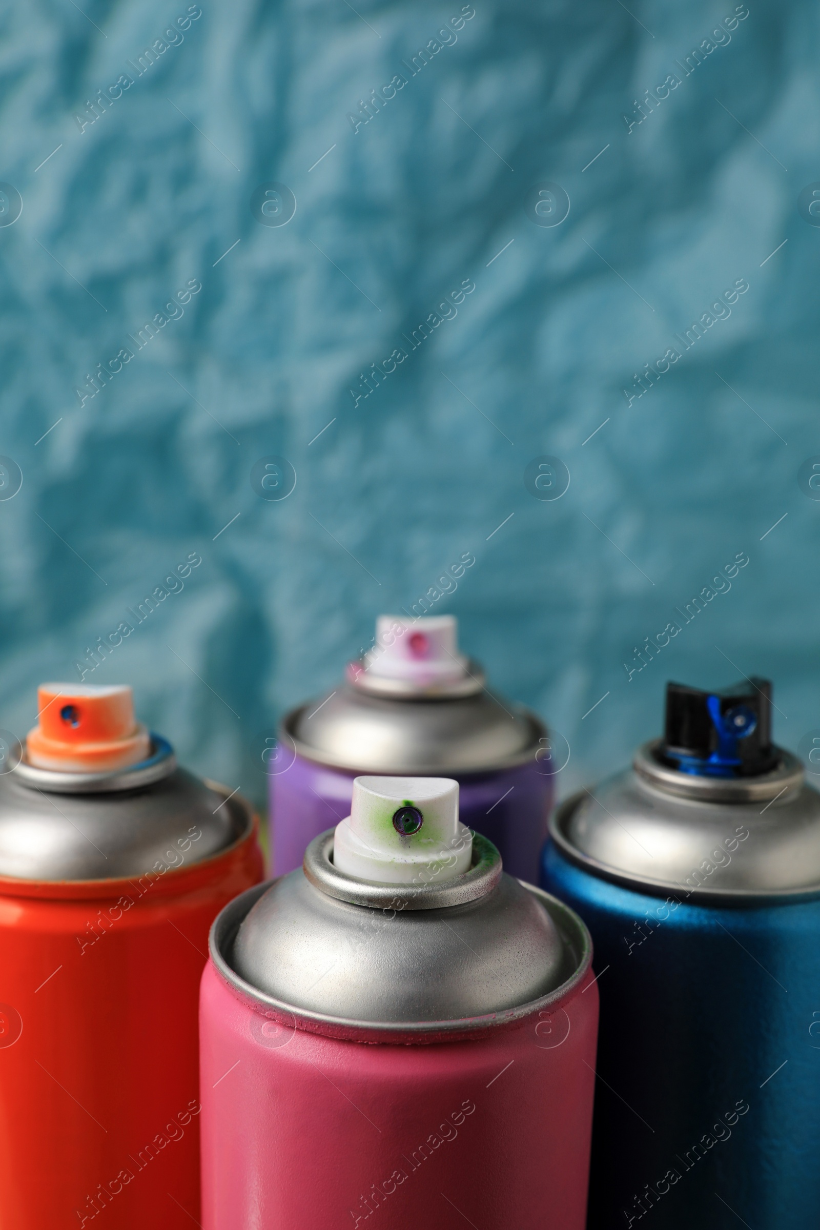 Photo of Cans of different graffiti spray paints on blurred background, closeup. Space for text