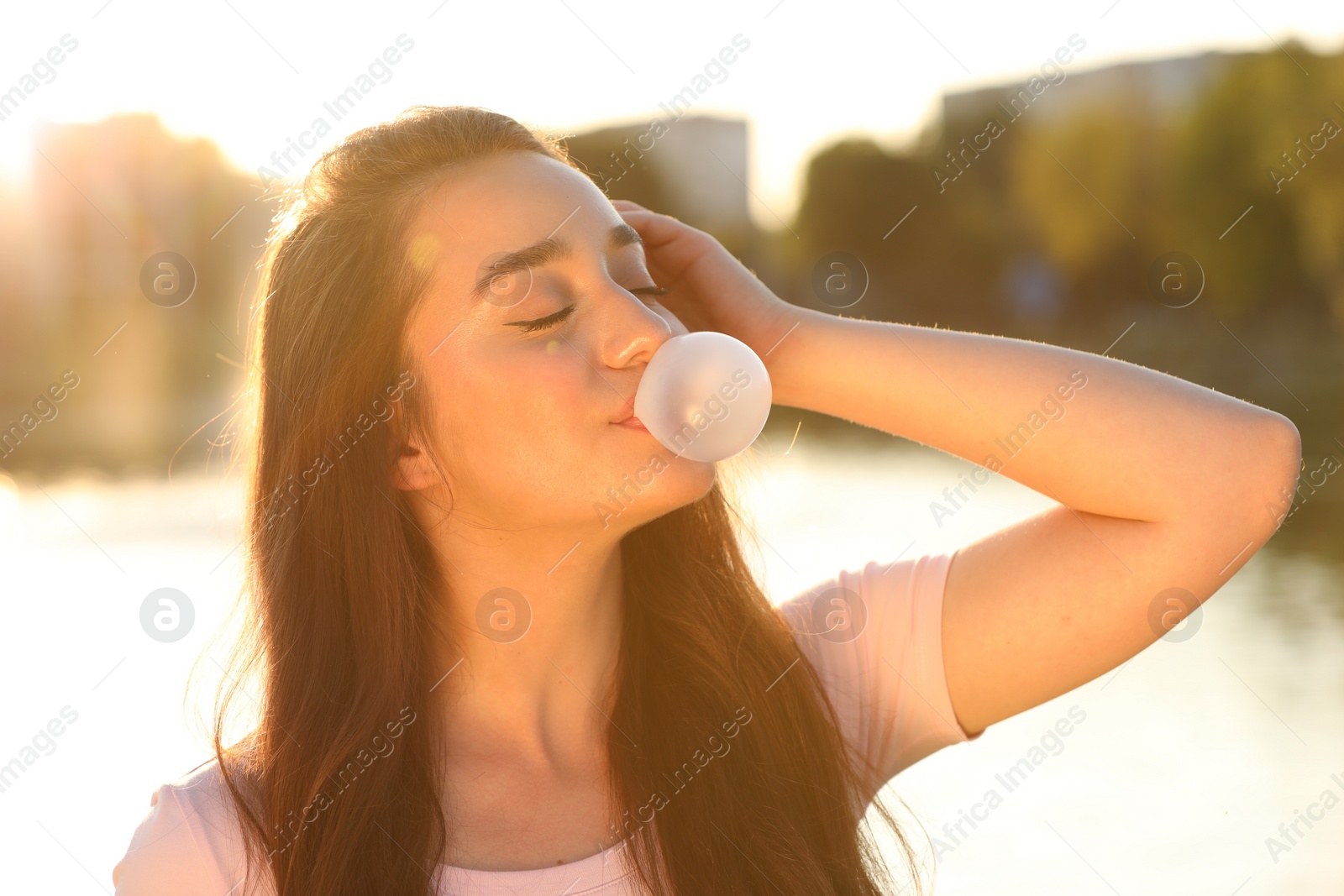 Photo of Beautiful young woman blowing bubble gum outdoors