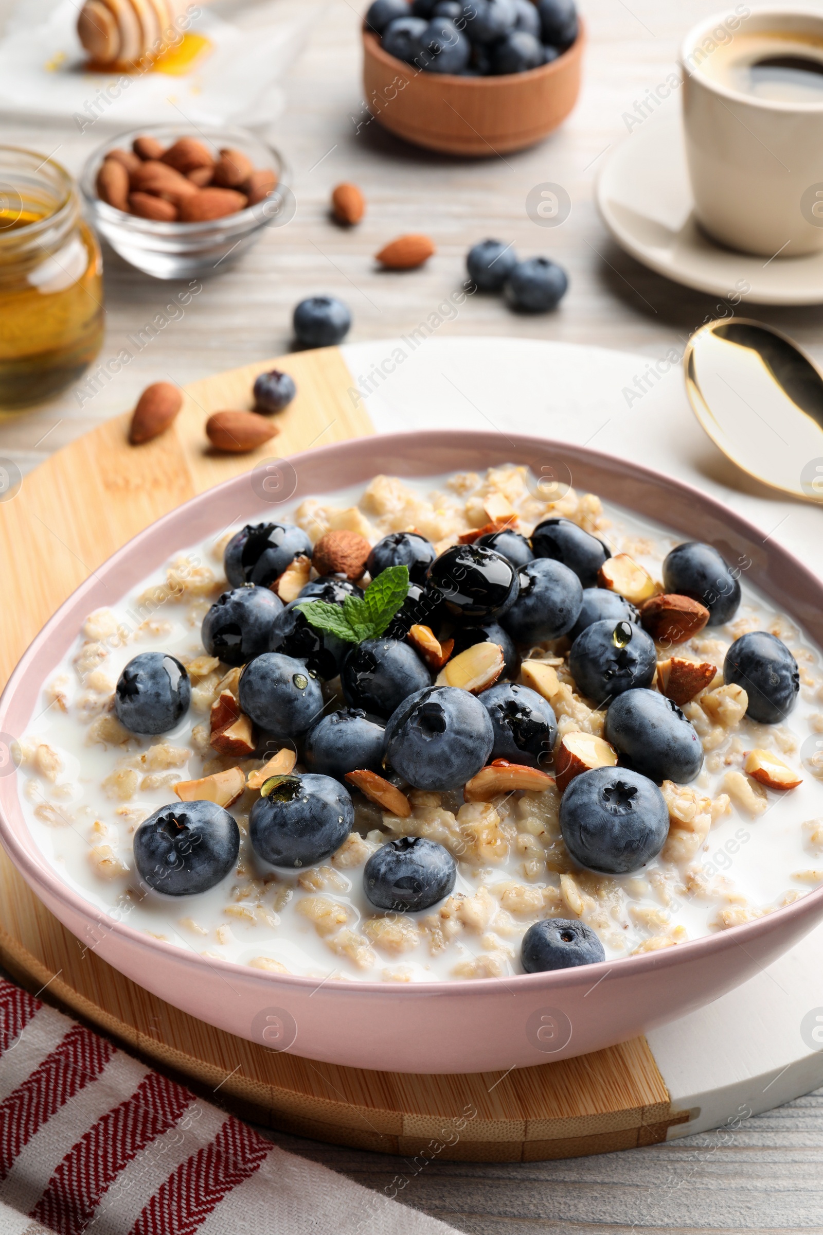 Photo of Tasty oatmeal porridge and ingredients served on wooden table. Healthy meal