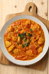 Photo of Delicious chicken curry on wooden table, top view