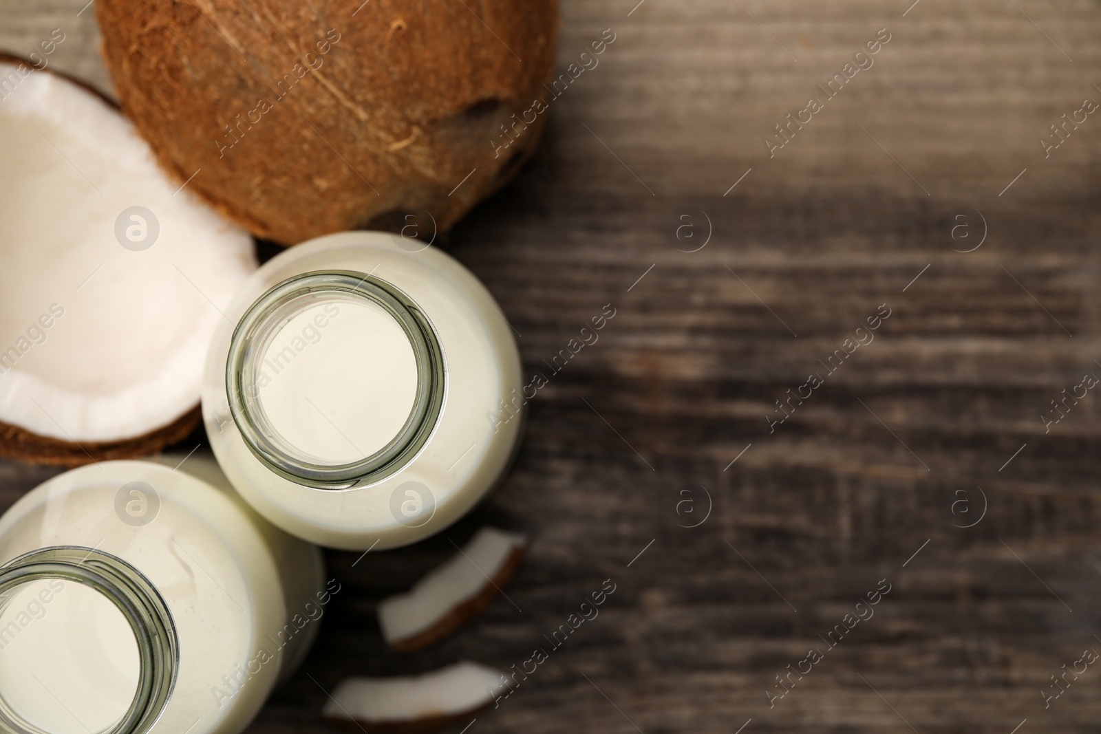 Photo of Delicious vegan milk and coconuts on wooden table, flat lay. Space for text