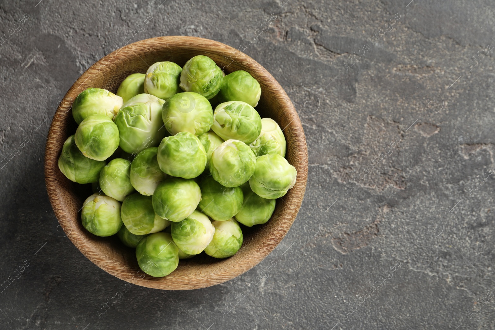 Photo of Bowl of fresh Brussels sprouts on grey background, top view with space for text