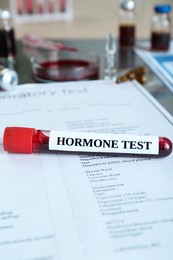 Photo of Glass tube with blood sample and label Hormone Test on table