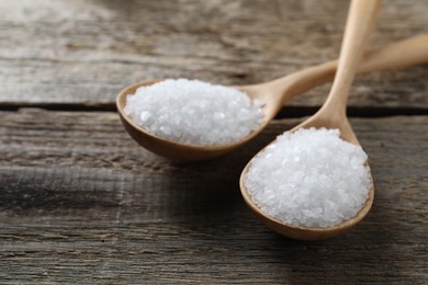 Organic salt in spoons on wooden table, closeup