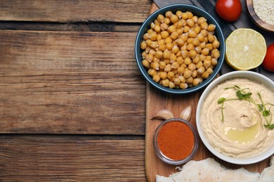 Photo of Delicious hummus with microgreens and different ingredients on wooden table, flat lay. Space for text