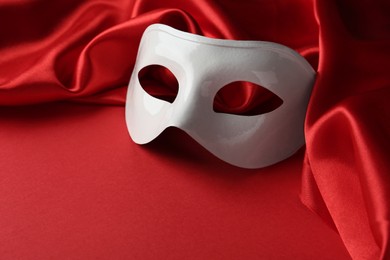 Photo of White theatre mask and fabric on red background