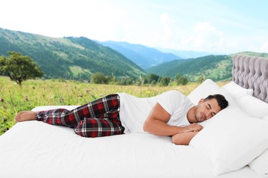 Man sleeping on bed with soft pillows and beautiful view of mountain landscape on background. Sleep well - stay healthy