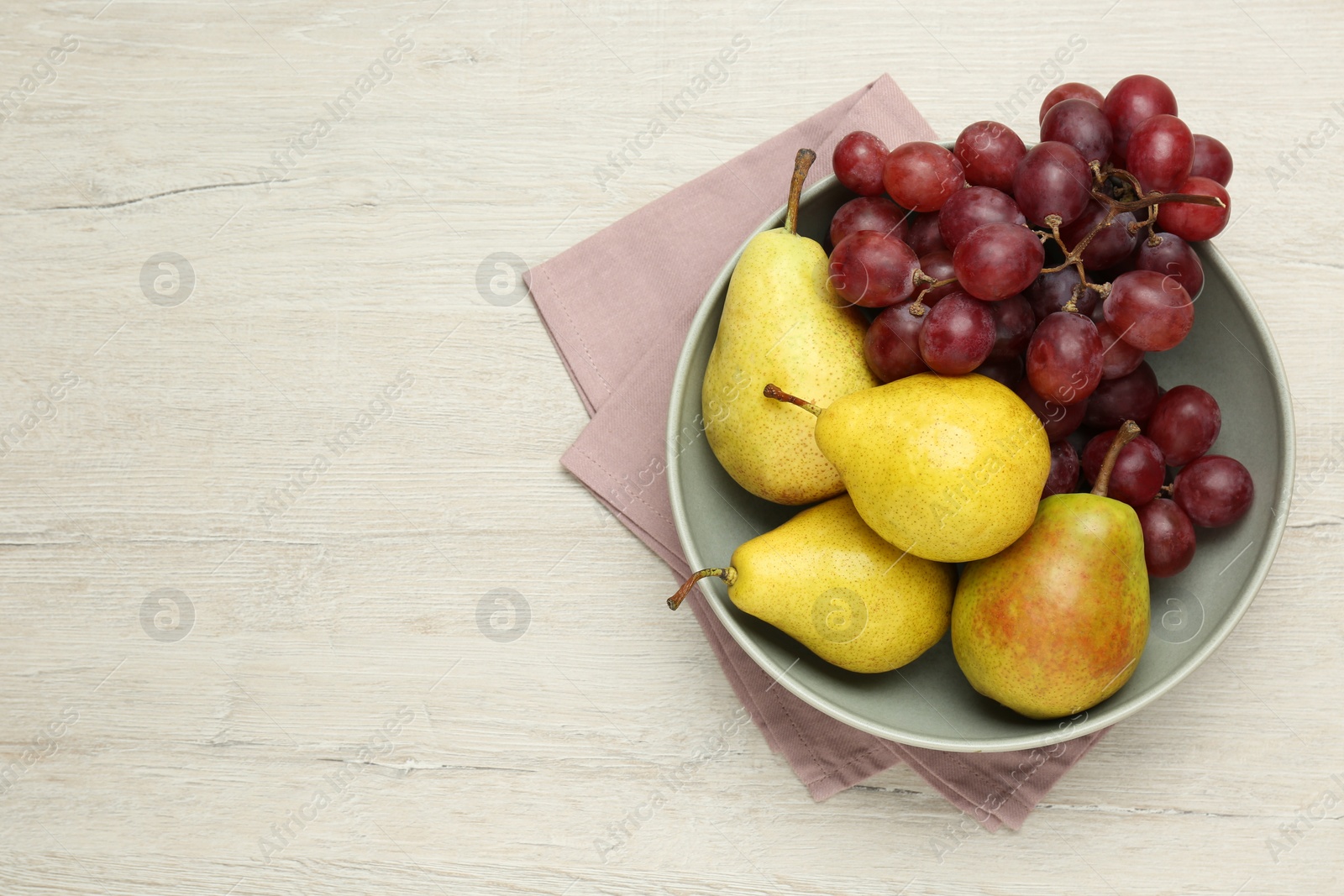 Photo of Fresh ripe pears and grapes on light wooden table, top view. Space for text