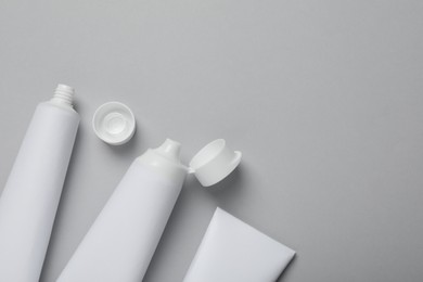 Photo of Blank tubes of toothpaste on light grey background, flat lay. Space for text