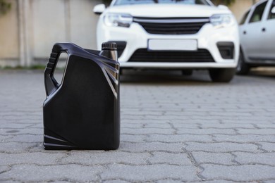 Photo of Canister with motor oil near car outdoors, space for text