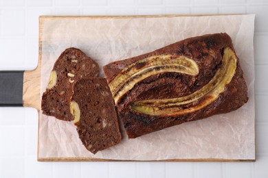 Photo of Delicious banana bread on white tiled table, top view